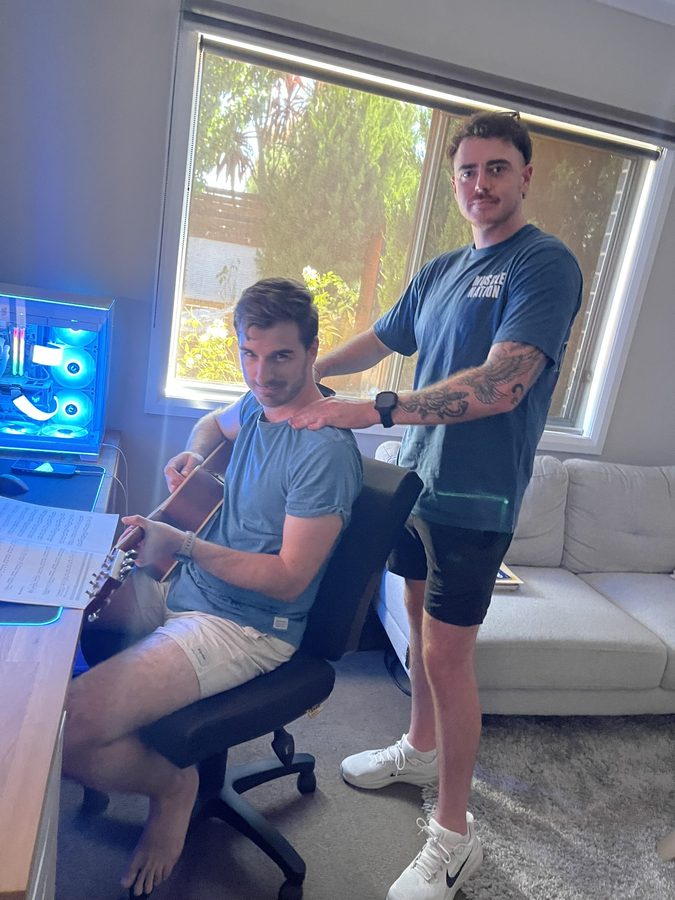 Jye playing acoustic guitar while receiving a shoulder massage