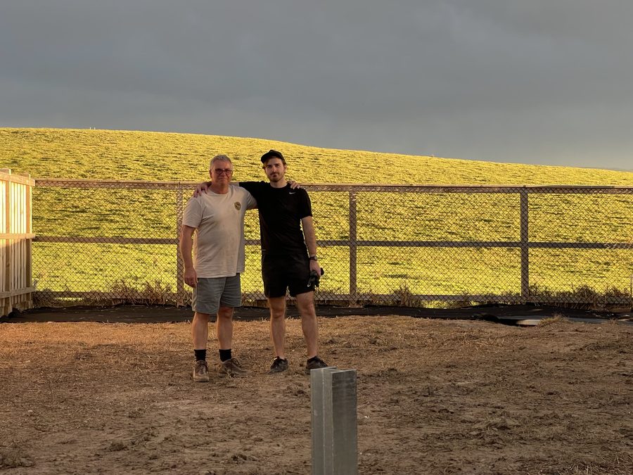Jye and his dad in front of a fence
