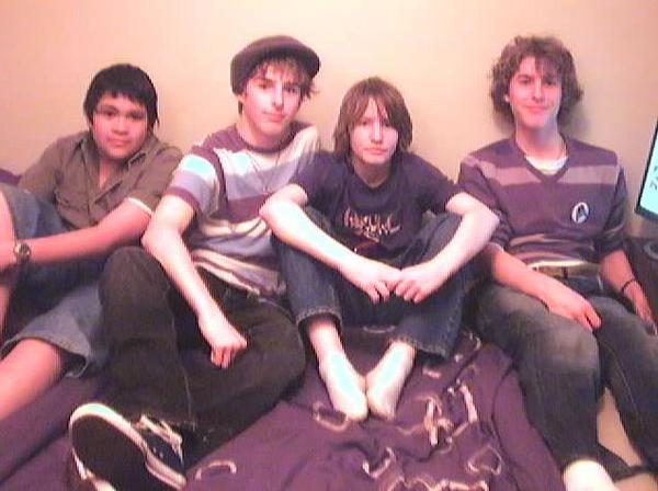 Four teenagers sitting on a bed